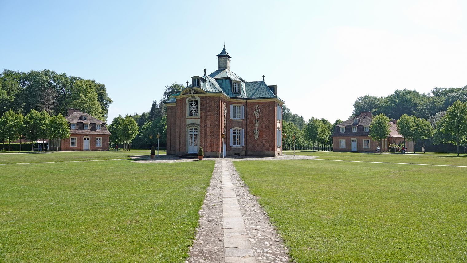 Barockes Schloss Clemenswerth mit symmetrischer Gartenanlage und flankierenden Pavillons im Grünen.