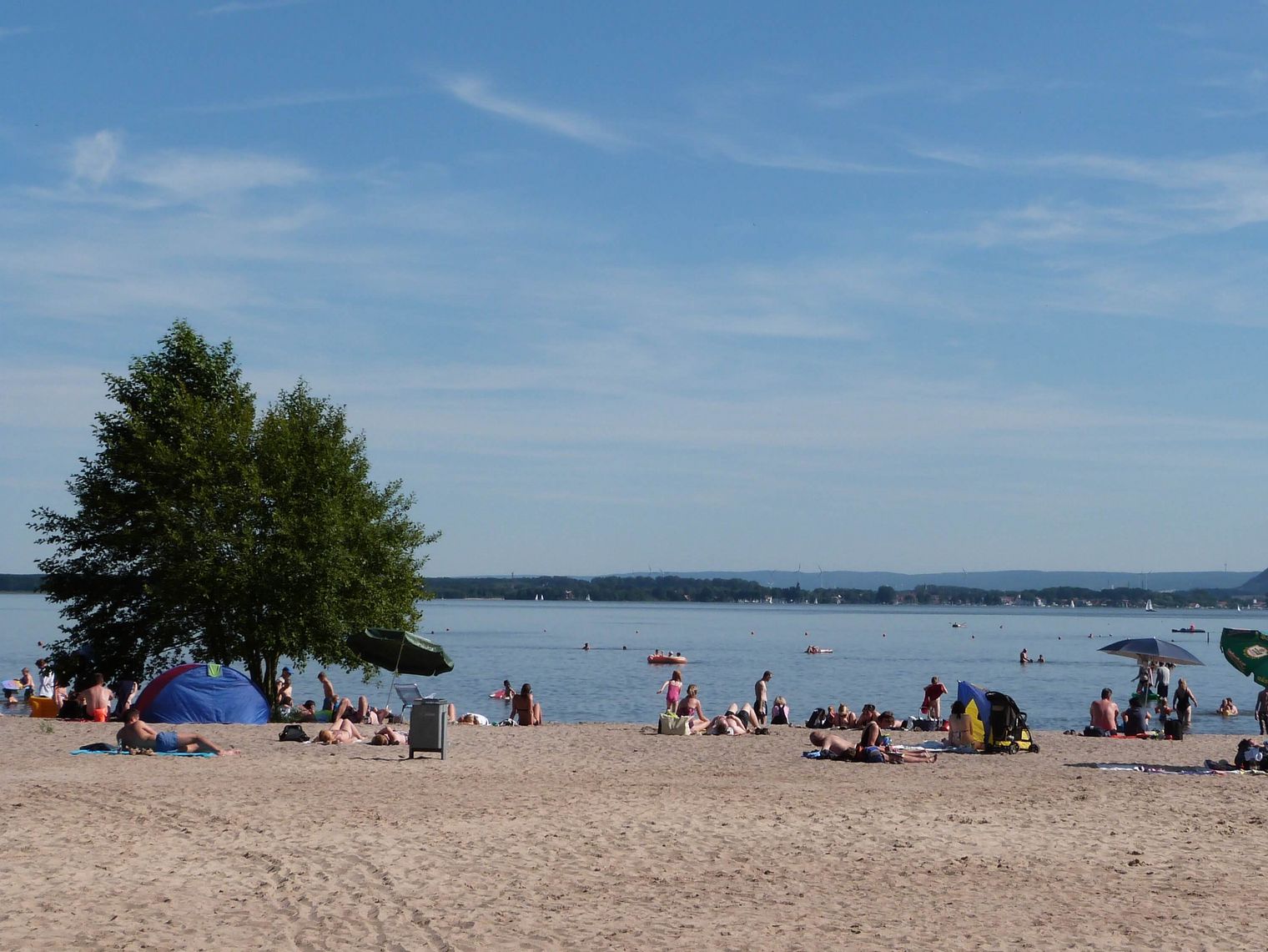 Der Badestrand in Mardorf, belebt und sonnig, lädt ein zum Entspannen am klaren, ruhigen Wasser.