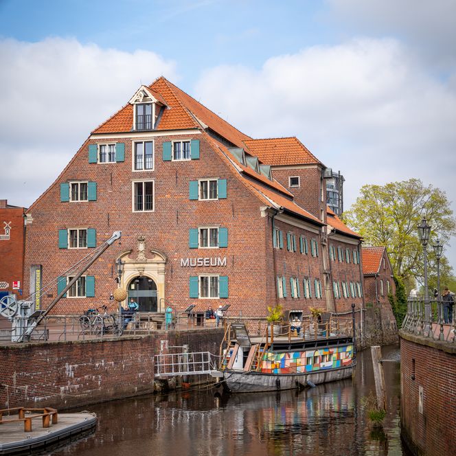 Schwedenspeicher-Museum am Stader Hansehafen mit historischem Kran und buntem Schiff.