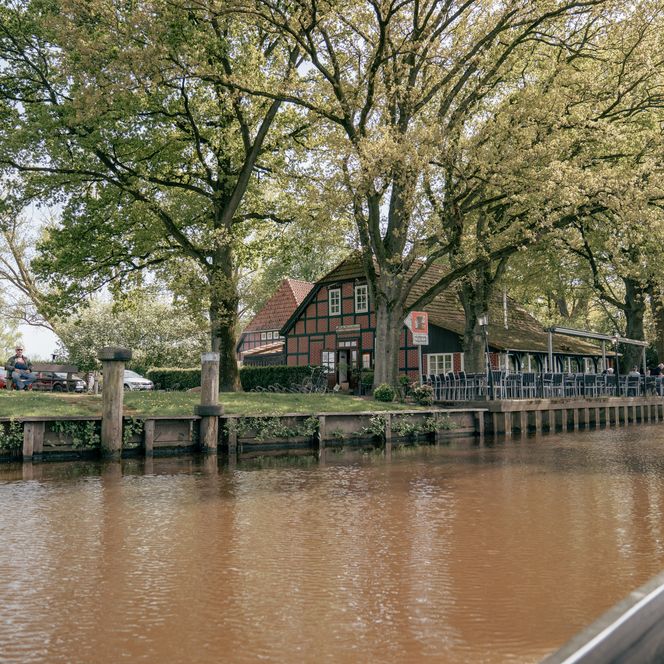 Fachwerkhaus mit Terrasse unter alten Bäumen am Flussufer der Hamme in Worpswede.