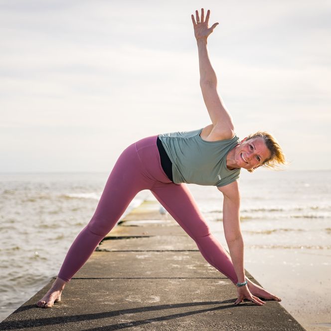 Frau macht auf Steg am Wasser Yoga