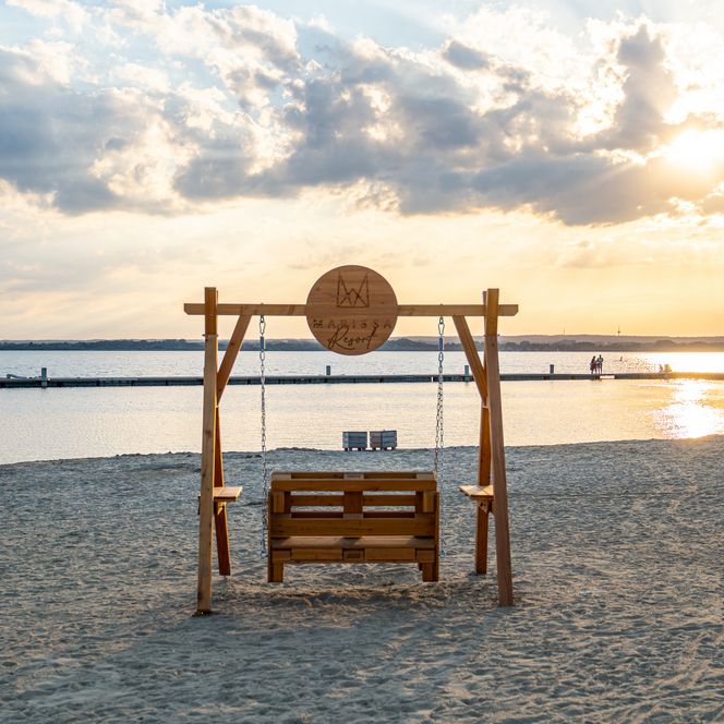 Holzschaukel am Sandstrand des Dümmer-Sees im Abendlicht.