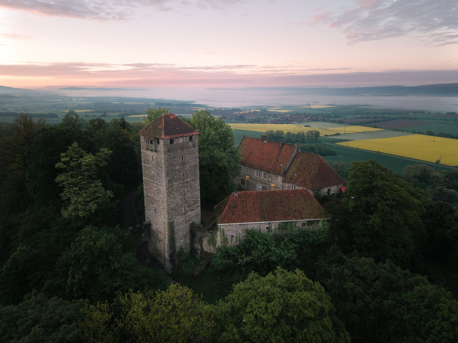 Burg Schaumburg mit Turm über dem nebligen Wesertal im Morgenlicht.