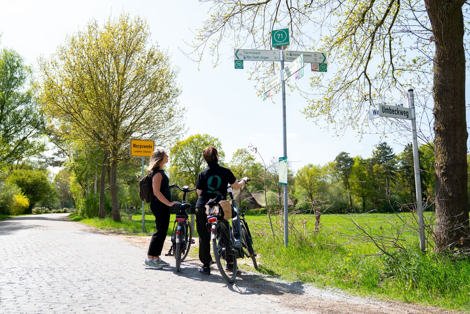 Zwei Radfahrerinnen betrachten einen Wegweiser.