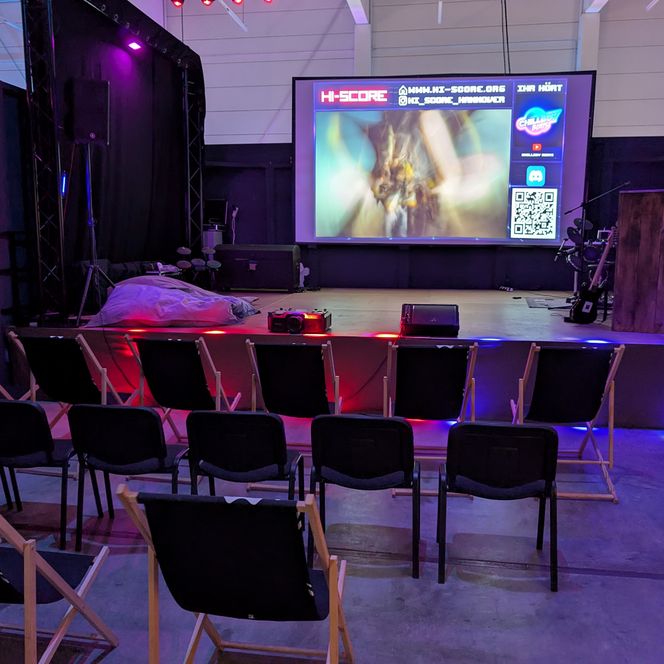 Eventbühne mit bunten Lichtern und einer Projektion an der Leinwand.