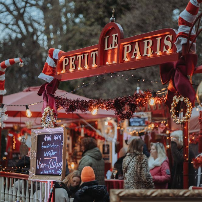 Weihnachtlich geschmückter Marktstand mit Lichterketten und Besuchern beim Schloss Bückeburg.