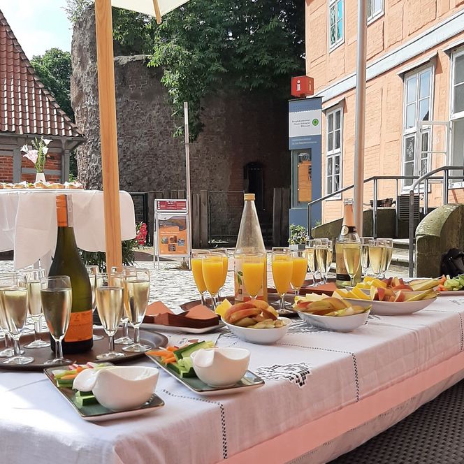 Festlich gedeckter Tisch mit Sekt, Saft und Obstschalen im Innenhof eines Schlosses.