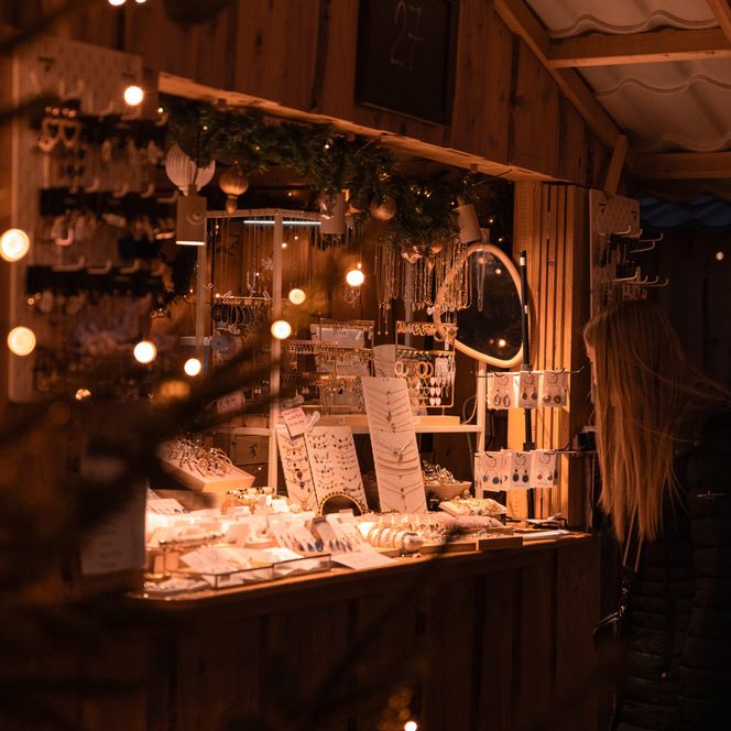 Holzstand mit funkelnden Lichtern und Schmuckauslage auf dem Weihnachtsmarkt in Burg Bentheim.
