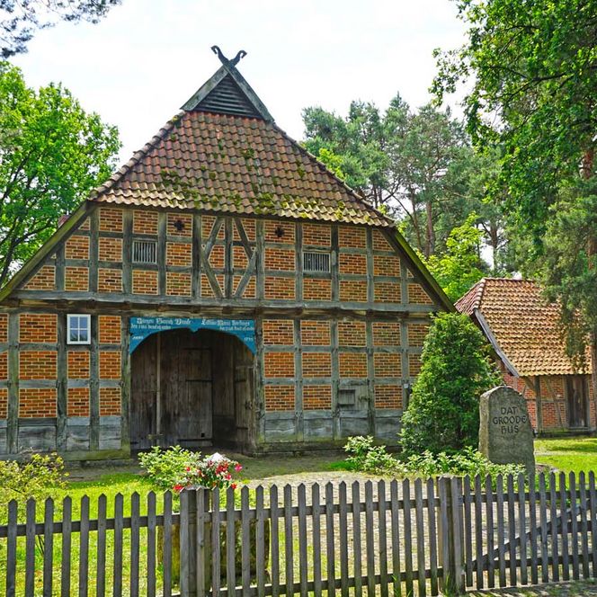 Historisches Fachwerkhaus "Dat Groode Hus" in Winsen (Aller) hinter einem Holzzaun im Grünen.