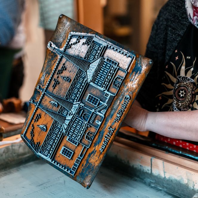 Person druckt mit Holzmodel auf Stoff bei einem Blaudruck-Workshop in Einbeck.