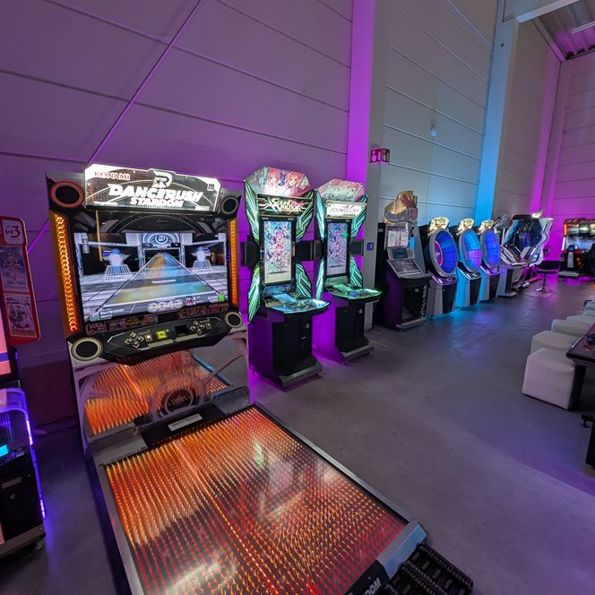 Ein heller, geräumiger Raum gefüllt mit leuchtenden Arcade-Automaten in einer modernen Halle.
