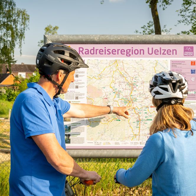 Zwei Personen stehen mit dem Rücken zugewandt vor einer Infotafel
