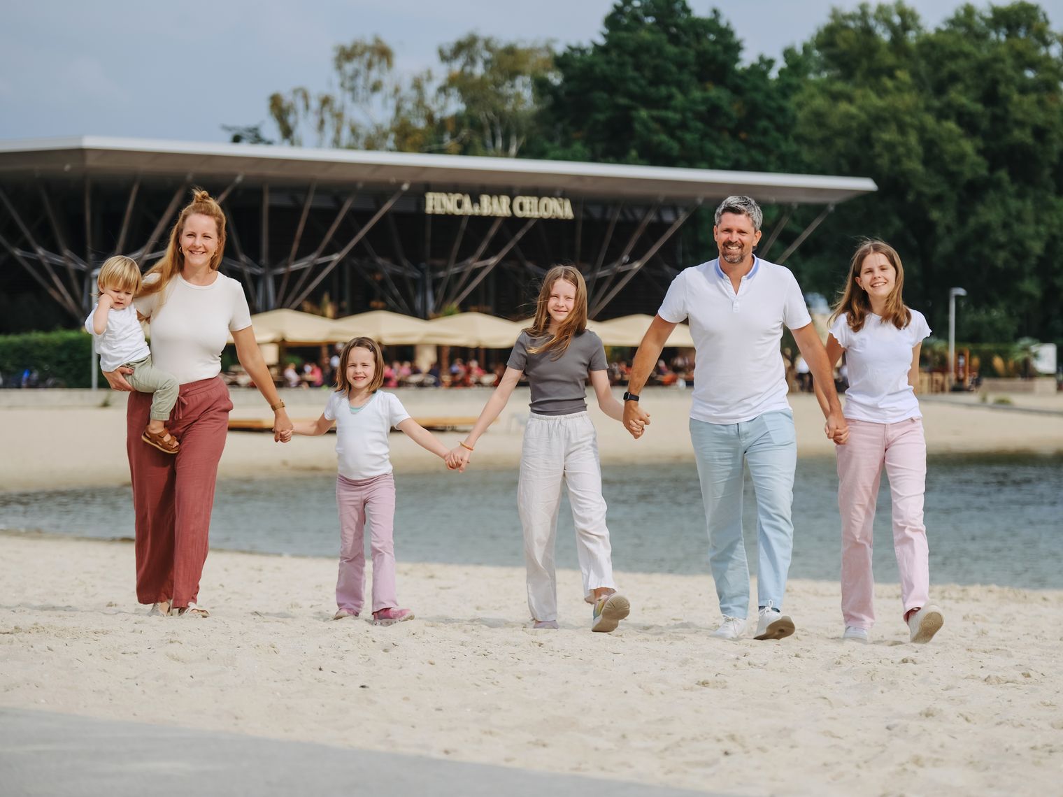 Familie läuft Hand in Hand am Sandstrand des Allersees in Wolfsburg.