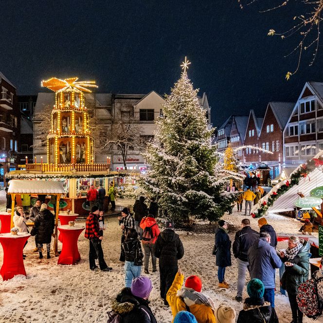 Winterlicher Weihnachtsmarkt in Stade mit beleuchtetem Tannenbaum, Buden und Menschen im Schnee
