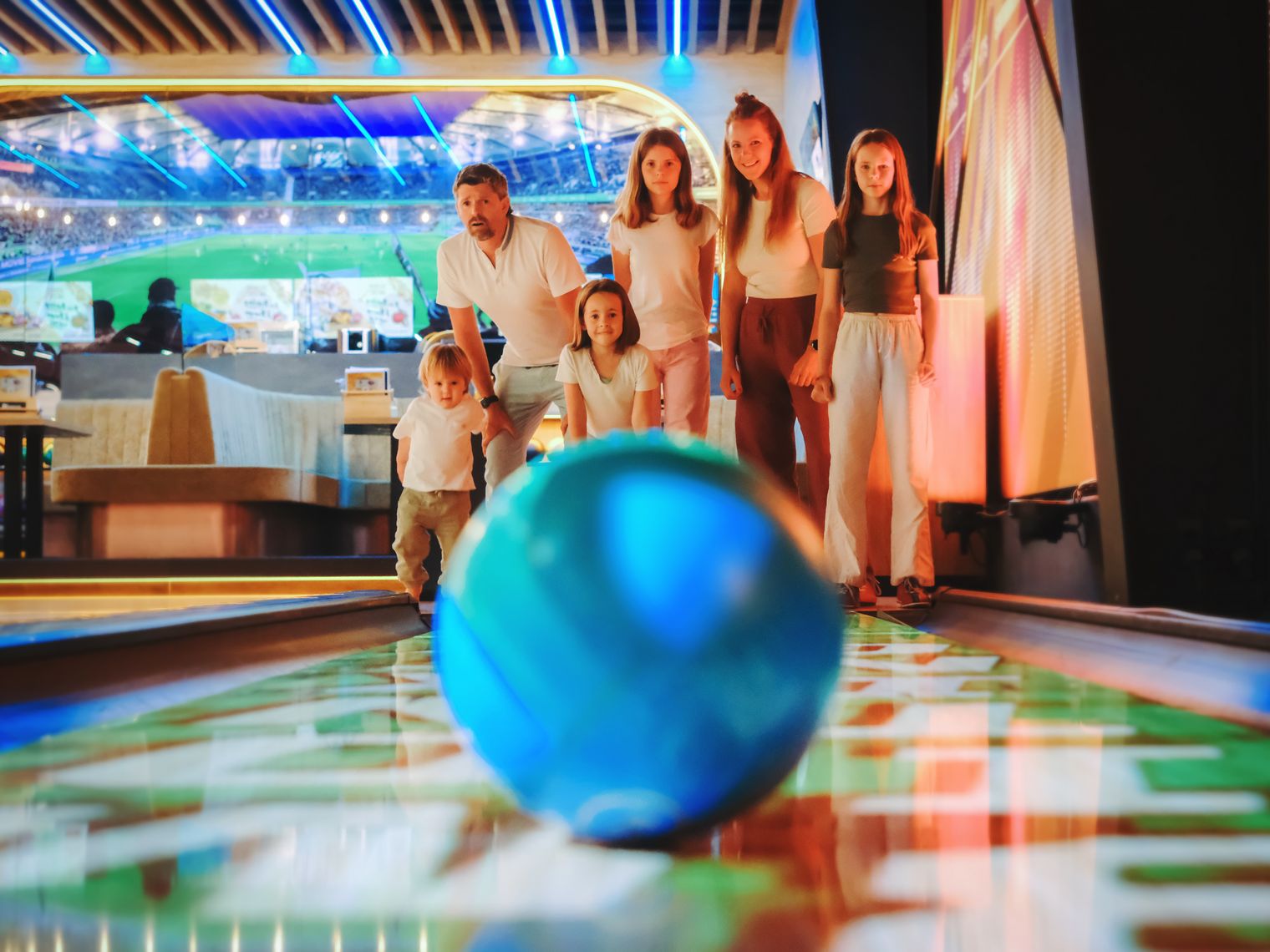 Familie beim Bowling mit blauem Ball auf leuchtender Bahn in Wolfsburg.
