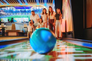 Familie beim Bowling mit blauem Ball auf leuchtender Bahn in Wolfsburg.