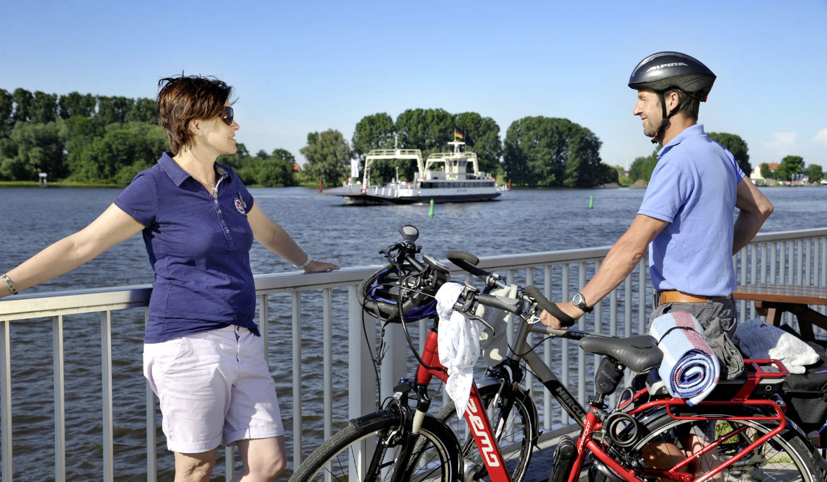 Zwei Radfahrer stehen an einer Reling an der Elbe., © Elberadweg Nord/ J.Harbeck