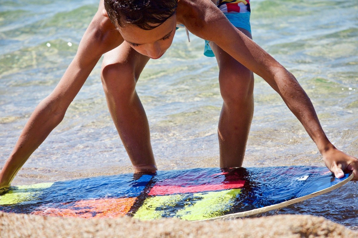 Junge mit Surfbrett am Strand, © Luisella Planeta Leoni