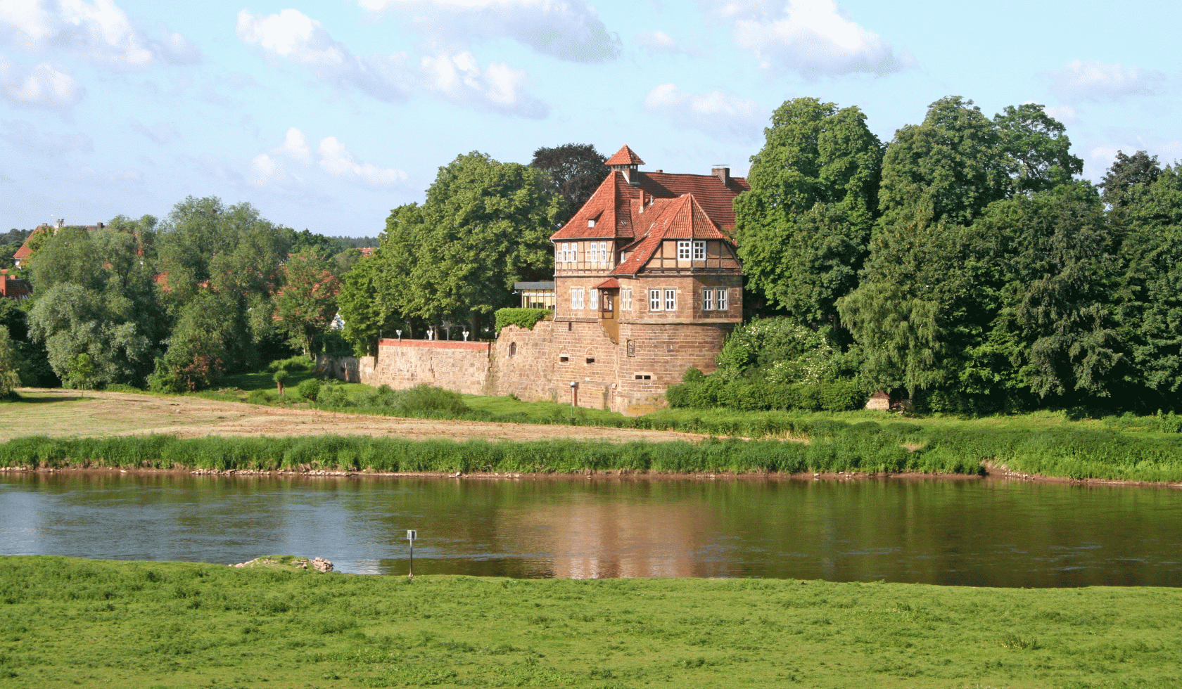 Das Schloss in Petershagen hinter dem fließenden Fluss und den grünen Wiesen., © Mittelweser-Touristik GmbH