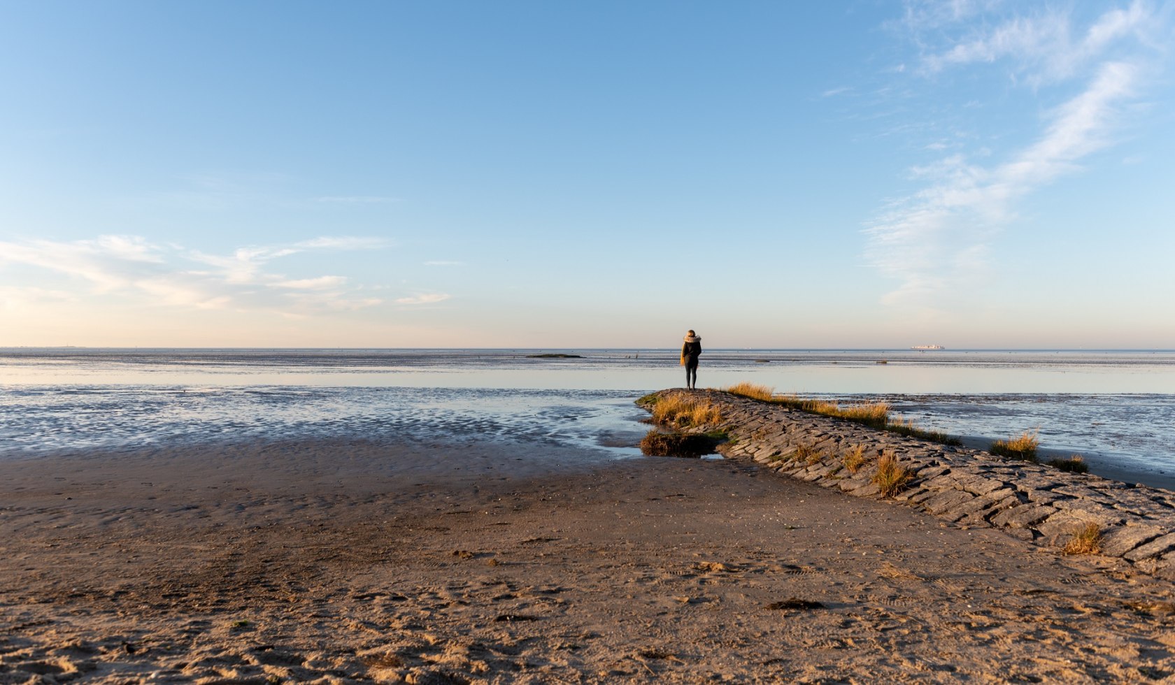 Cuxhaven Mensch auf einem Steinsteg am Wasser, © Alexander Kassner/ Alex K. Media