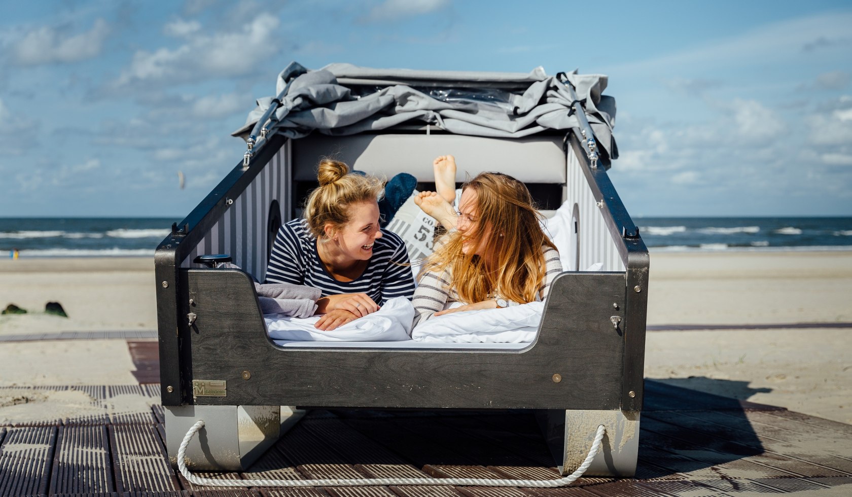 Schlafstrandkorb Norderney in dem zwei Mädchen liegen und sich anlachen, © Staatsbad Norderney GmbH, Janis Meyer
