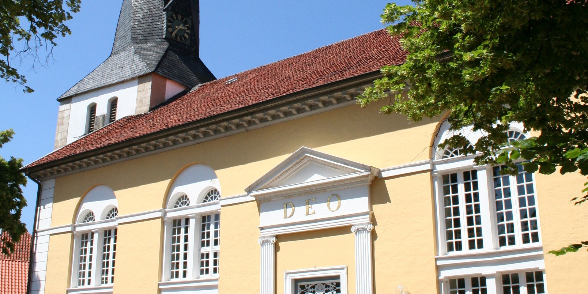 Die St. Jacobi Kirche Stolzenau strahlt in freundlichem gelb unter dem blauen Himmel., © Mittelweser-Touristik GmbH