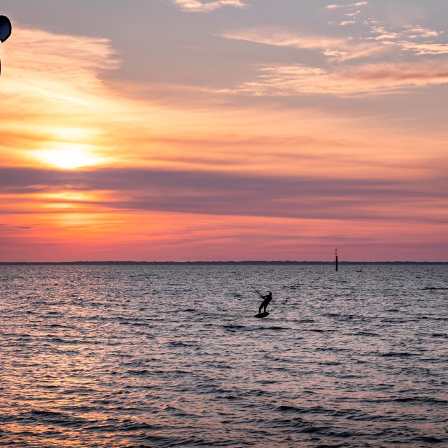 Kitesurfer auf dem Wasser im Sonnenuntergang., © Chris Hoppe
