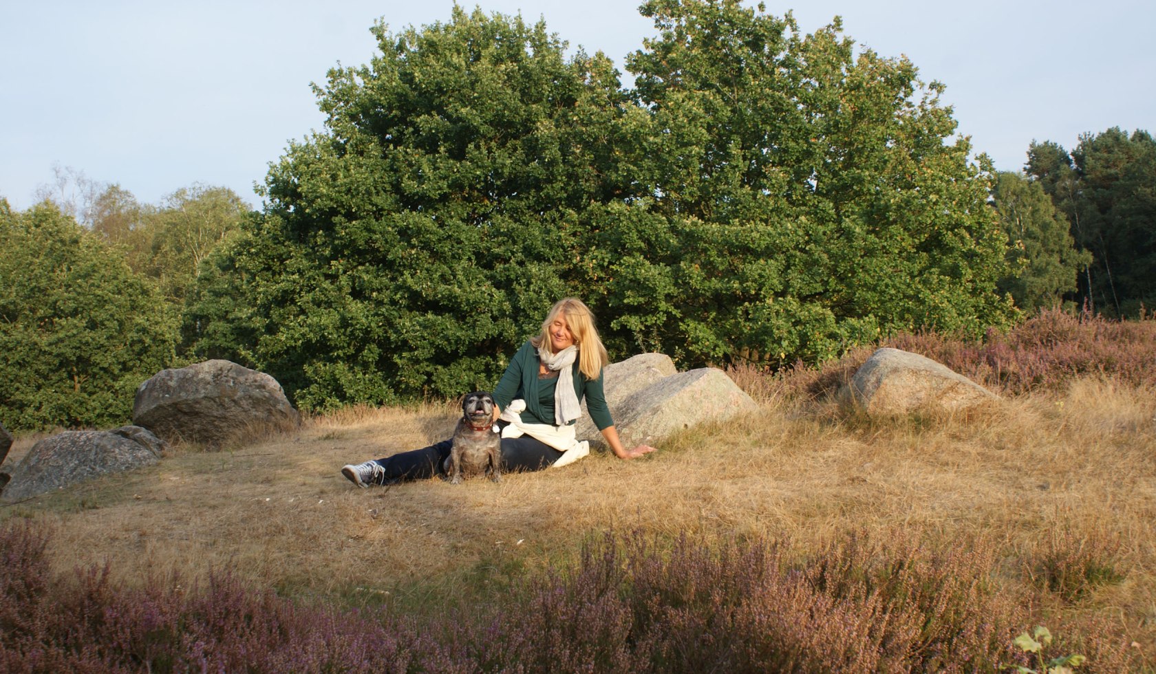 Frau mit Hund sitzt bei den Großsteingräbern Glaner Braut, © Jörg Guhn