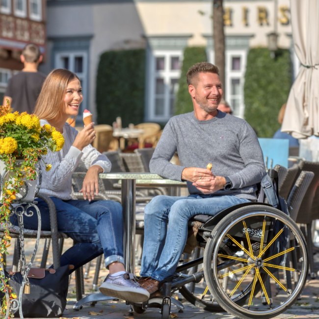Ein Paar, der Mann sitzt im Rollstuhl, genießt ein Eis in der Sonne., © TMN/ Christian Bierwagen