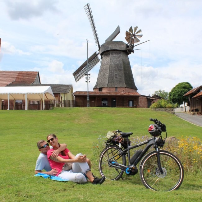 Radfahrer legen Pause neben einer Mühle ein, © Mittelweser Touristik GmbH