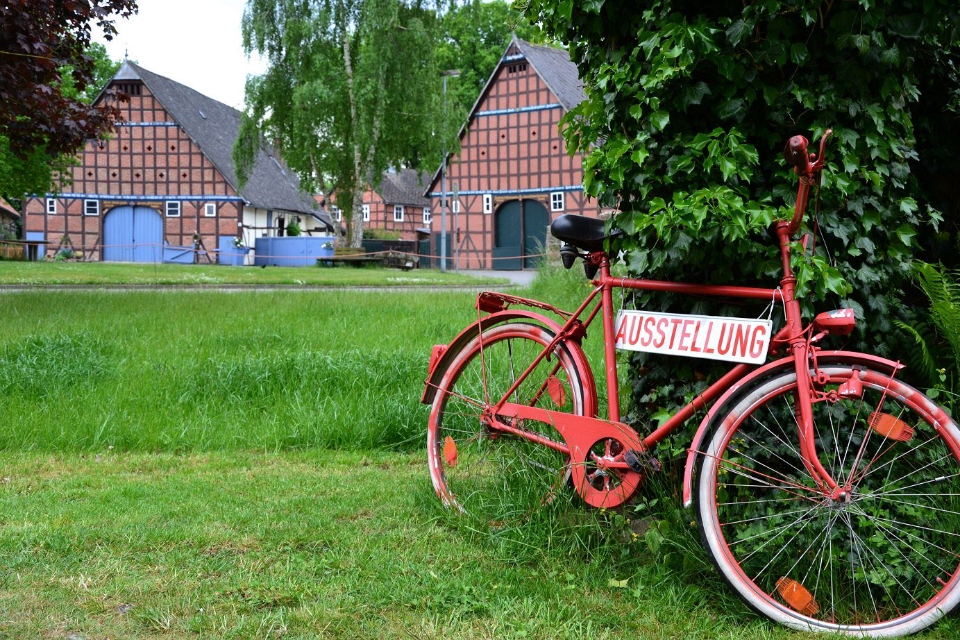 Vor einem Rundling steht ein rotes Fahrrad mit der Aufschrift &quot;Austellung&quot;, © Marketingbüro Wendland.Elbe