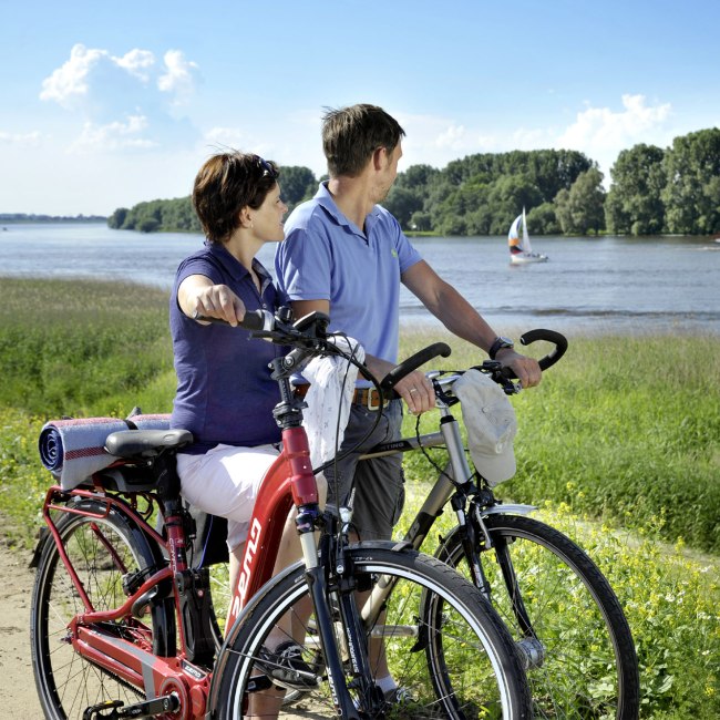 Zwei Radfahrer machen bei schönem Wetter eine Pause und schauen auf den Fluss Luhe., © Elberadweg Nord/ J.Harbeck