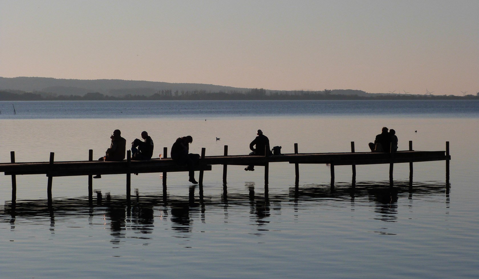 Menschen sitzen auf einem Bootssteg in Steinhude im Abendlicht, © Steinhuder Meer Tourismus GmbH / F. Toffel