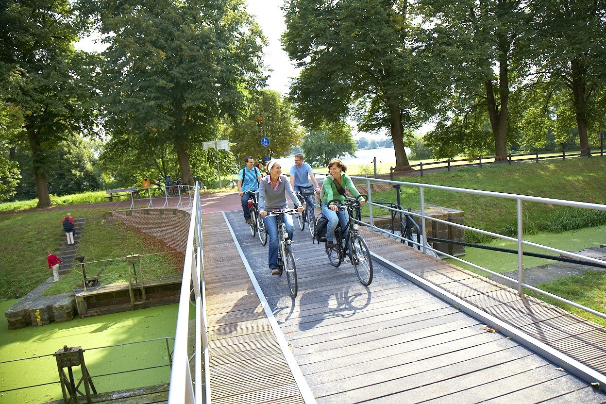 Radfahrer auf der Schleusenbrücke mit dem Vechtesee im Hintergrund, © Grafschaft Bentheim Tourismus e.V./ Schubert