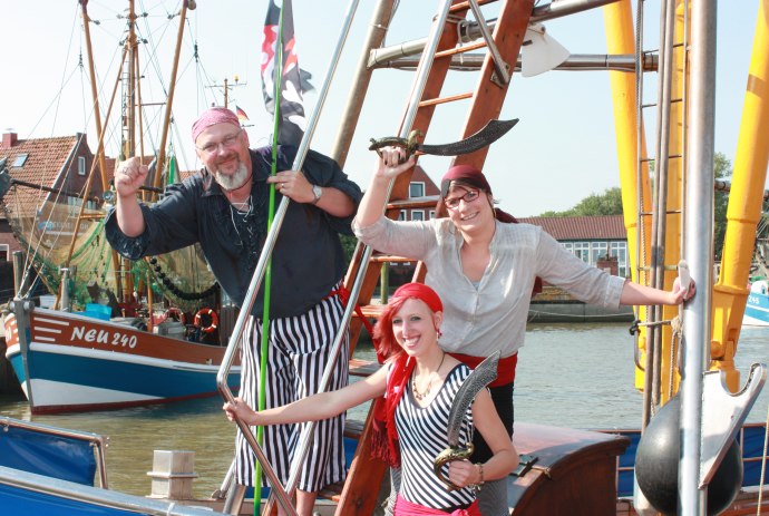 Drei Erwachsene als Piraten verkleidet stehen auf einem Boot., © Kurverein Neuharlingersiel e.V.