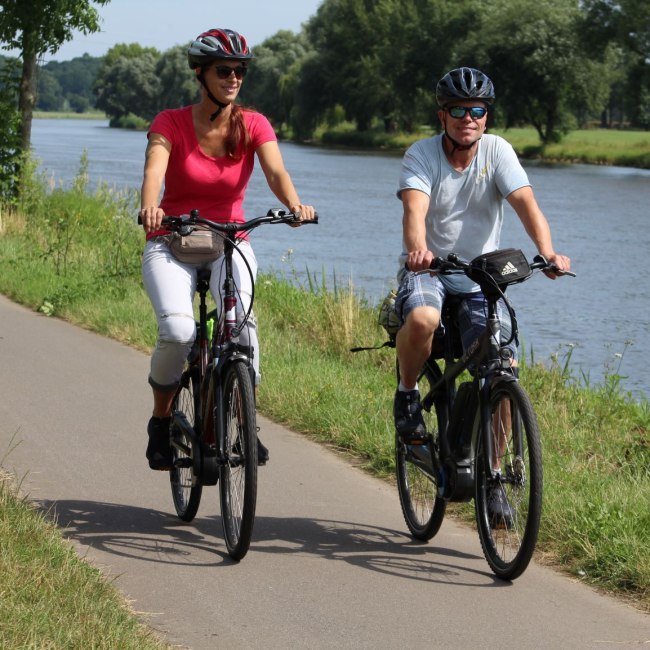 Paar fährt Fahrrad auf Radweg neben der Weser, © Mittelweser Touristik GmbH