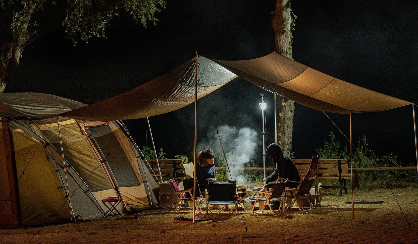 Zwei Männer sitzen an einem Grill vor einem Zelt , © TMN/pixabay