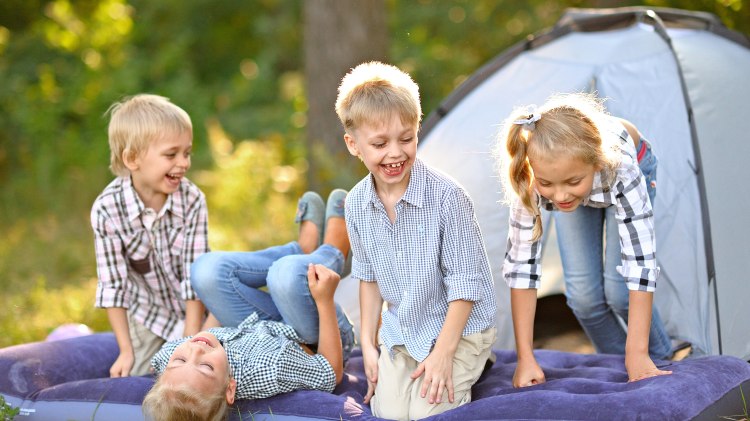Mehrere Kinder sitzen vor einem Zelt im Grünen., © Fotolia/ zagorodnaya
