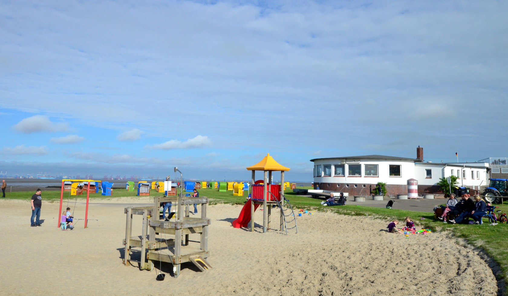 Ein Spielplatz am Strand mit einer Schaukel und zahlreichen Klettermöglichkeiten. Im Hintergrund sind Strandkörbe zu sehen., © Elischeba Wilde