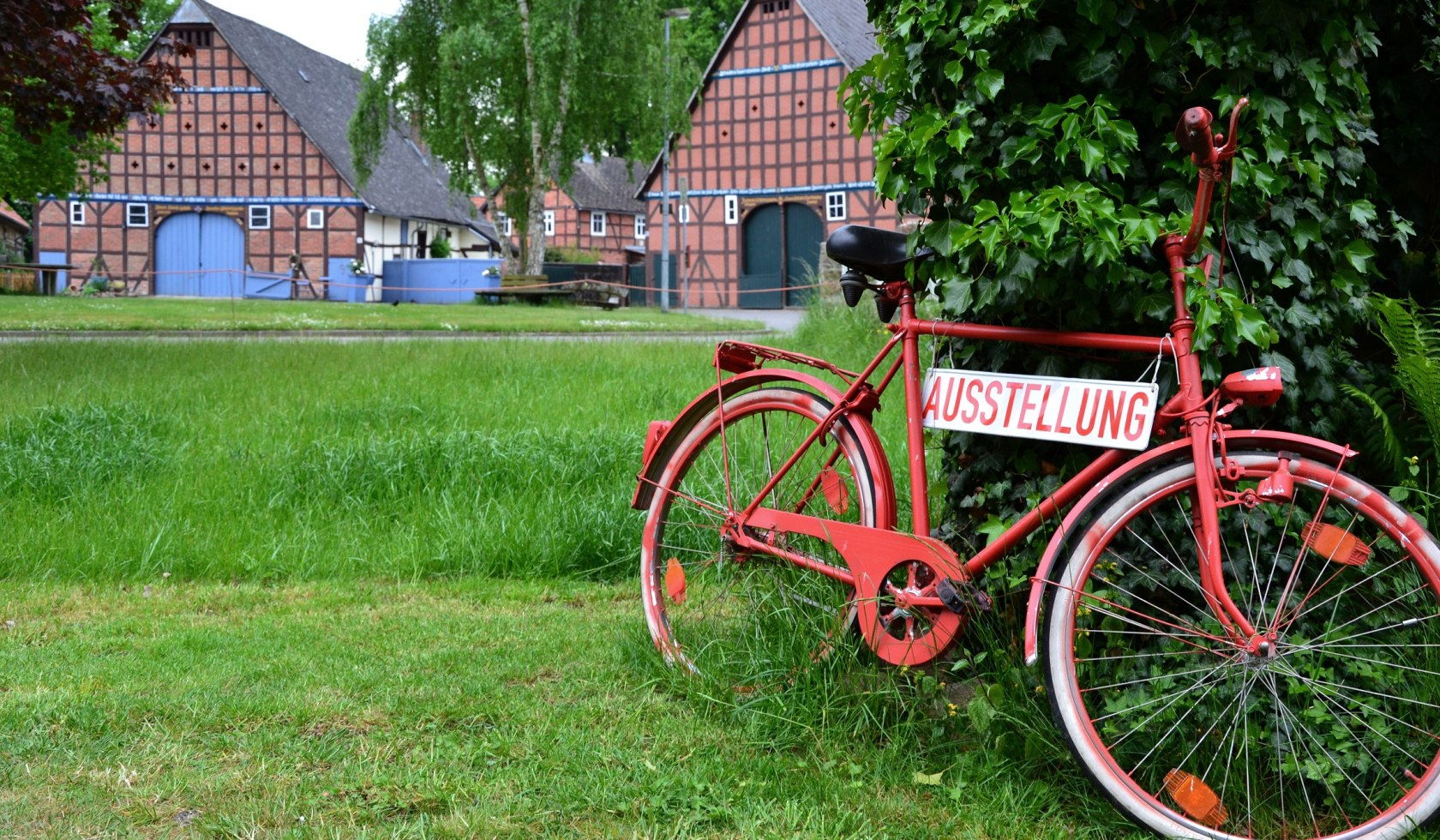 Ein rotes Fahrrad mit der Aufschrift "Ausstellung" lehnt am Baum., © Marketingbüro Elbe.Wendland / Laura Selenz