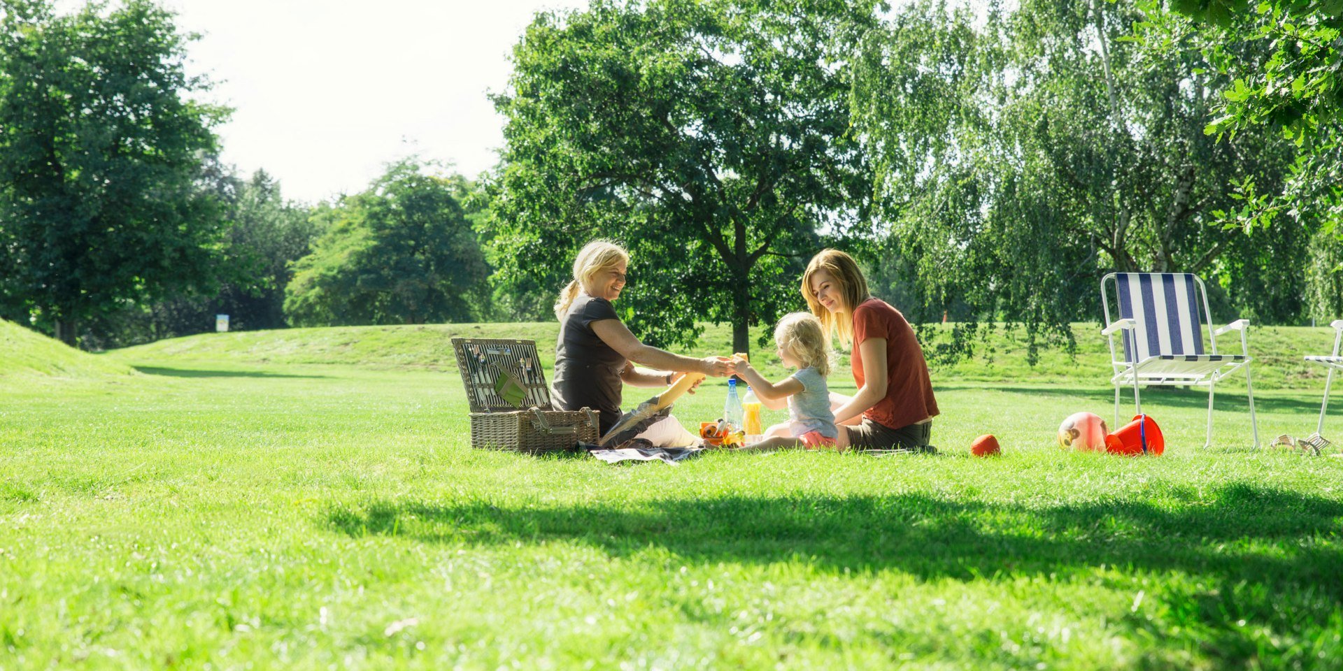 Zwei Frauen und ein Kleinkind machen ein Picknick im Allerpark, © Wolfsburg AG / Jenko Sternberg