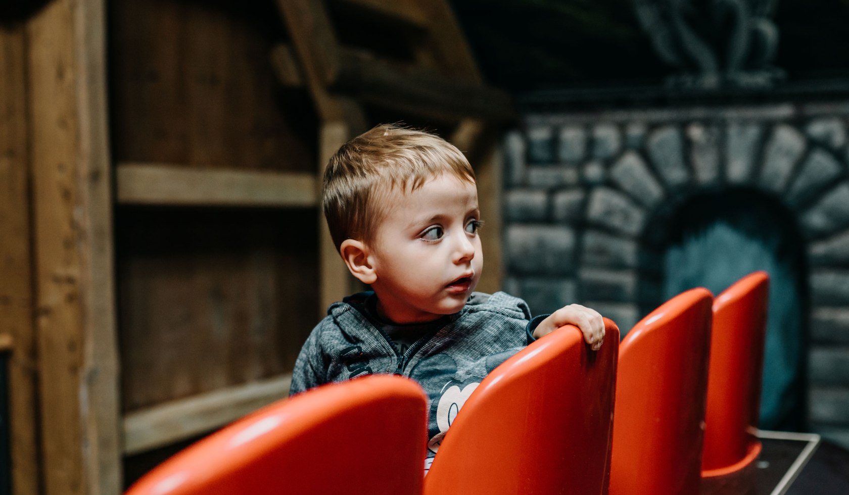 Kleiner Junge auf einem roten Stuhl in der Spielscheune Hof Frien, © Lia Falke