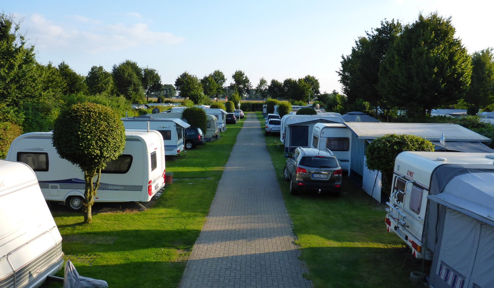 Ein gerader gepflegter Weg führ vorbei an Wohnmobilen und Wohnwagen., © Camping Hümmlinger Land / Albers
